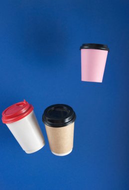 Tek kullanımlık kağıt, arka planda asılı duran kahve fincanlarıyla uçuyor. Paket kahve konsepti. Soyut arkaplan