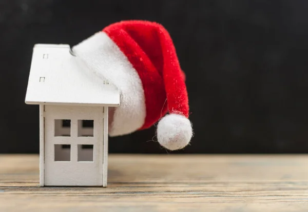 Santa Hatt Med Miniatyr Hus Modell Träbord — Stockfoto