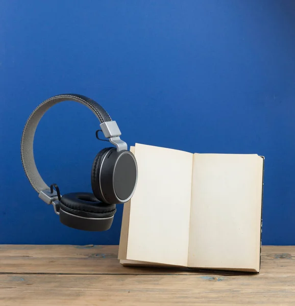 Headphones with book hover in the air. On a dark blue background.