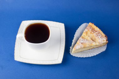 Mavi arka planda bir fincan sıcak kahve ve tatlı hamur işi.