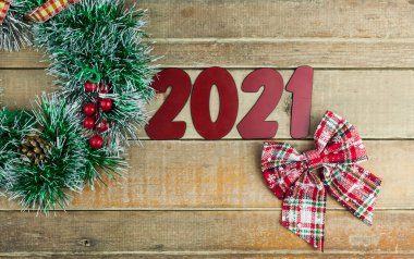 Noel çelengi ve 2021 numara. Ahşap arka planda Noel ağacı dalları, koniler ve oyuncaklar için yaratıcı bir tasarım. Üst manzara, kopya alanı, düz yerleşim. Yeni yıl ve Noel konsepti.