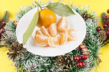 Sarı arka planda yeşil yapraklı taze portakal kasesi