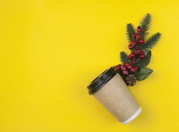 黄色の背景にクリスマスベリーの枝と使い捨てコーヒーカップ コンセプトクリスマス コピースペース トップ表示 — ストック写真