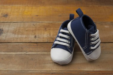 Tahta masada duran mavi spor ayakkabılı bebek.