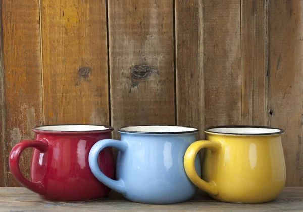 Ahşap arka planda üç renkli kahve fincanı.