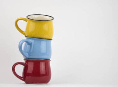 Beyaz arkaplanda renkli seramik kupalar yığını