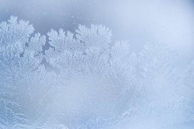 Kışın camda makro buz fotoğraflamak. Camın üzerinde mavi bir zemin üzerinde beyaz kar taneleri olan güzel şenlikli buz deseni.