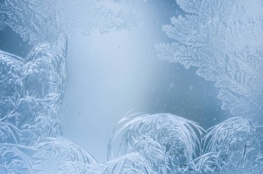 Kışın camda makro buz fotoğraflamak. Camın üzerinde mavi bir zemin üzerinde beyaz kar taneleri olan güzel şenlikli buz deseni.