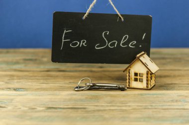 Gayrimenkul kavramı. Satılık ev. Gerçekten eski bir karatahta, minyatür evle birlikte satılık.