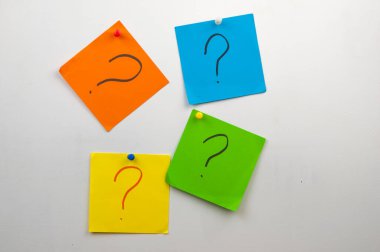 Duvarda bir sürü renkli not kağıdı ve soru işareti var.