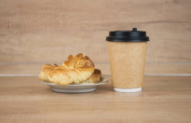 Ahşap masada kahve fincanı ile haşhaş tohumlu iki çörek. Kahvaltıda. İyi sabahlar. Kahve zamanı.