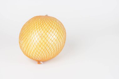 Olgun bir pomelo beyaz arkaplanda yer alan bir ızgarada paketlenir