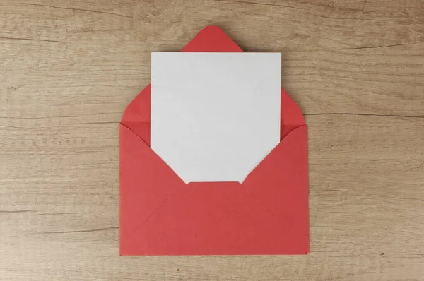 Blank white paper and red envelope on a wood table. Place for text or congratulations