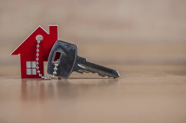 Ahşap masada metal anahtarı olan ev sembolü. Gayrimenkul, sigorta konsepti, ipotek, satın alma evi, emlakçı konsepti 