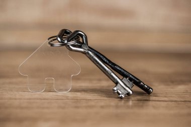 Ahşap masada metal anahtarı olan ev sembolü. Gayrimenkul, sigorta konsepti, ipotek, satın alma evi, emlakçı konsepti 