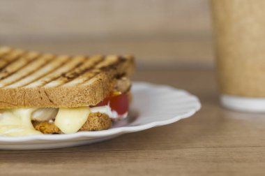 Jambonlu, peynirli, domatesli ve kızarmış ekmekli büyük bir sandviç.