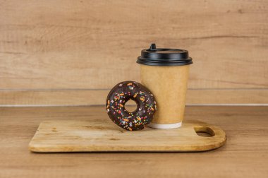 Çikolatalı donut ya da sıcak bir fincan taze kahveye yaslanmış donut. Kahvaltıda kahve ve çörek.