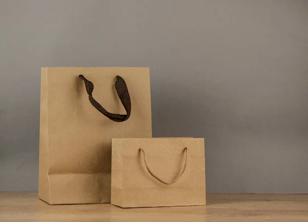 Set blank brown paper carrier bags with handles for shopping on wood table