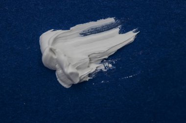 Mavi arkaplanda beyaz fırça darbelerinin dokusu.