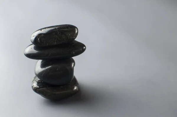 黑色按摩石堆在灰纸的背景上 塔中的卵石群 和谐与平衡 — 图库照片