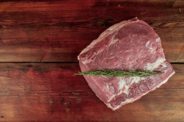 Ahşap masada büyük bir parça çiğ domuz boynu. Baharatlı domuz filetosu ve ahşap arka planda biberiye. yakın çekim, telif alanı, üst görünüm