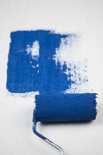 ローラーブラシ塗装 暗い青の色の塗料で改装された表面壁の塗装アパートの労働者の絵画 空のコピースペースを空白にして横に記述テキストを書く — ストック写真