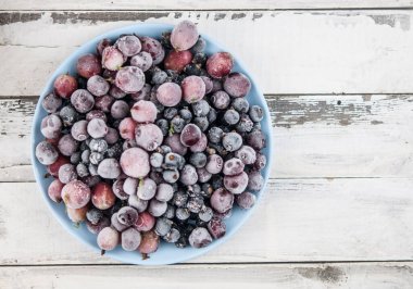 Donmuş meyve arkaplanı seramik tabakta. Meyveler buzlu. antika beyaz tahta tahtalar üzerinde, metin için boşluk, kopyalama alanı