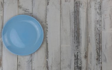 Kırsal beyaz ahşap bir masada boş bir seramik tabağın üst görüntüsü