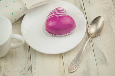 Masanın üzerinde kalp şeklinde kırmızı bir pasta var. Romantik randevu