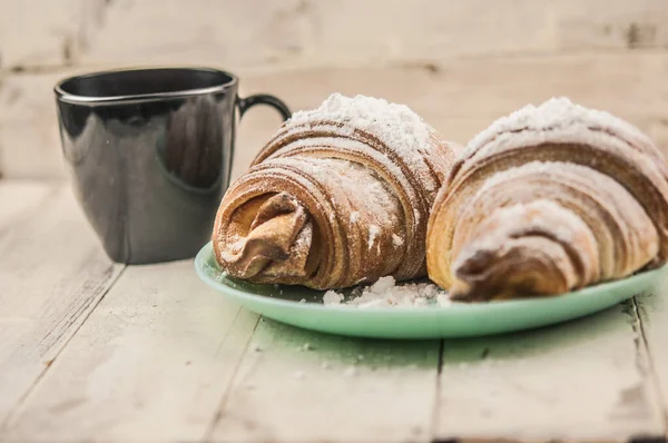 Beyaz ahşap masada iki taze kruvasan. Kahvaltı.