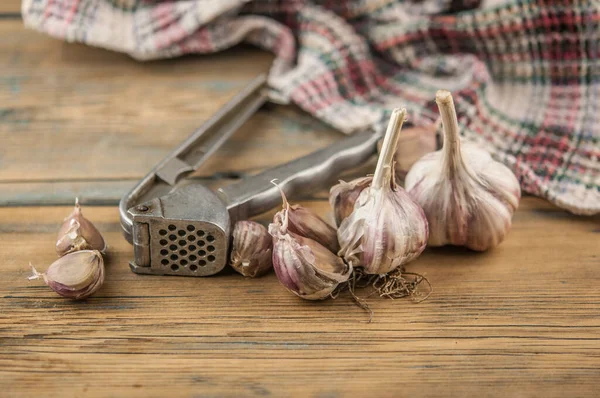 金属压榨机的有机大蒜 新鲜大蒜丁香和大蒜球茎放在木制桌子上 用于健康饮食的大蒜 健康烹调的香料概念 — 图库照片