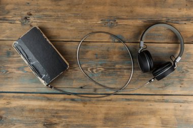 Ses kitabı konsepti. Kulaklıklar ve eski kitaplar ahşap masanın üzerinde. Metnin için en üstte boşluk var. Uzaktan eğitim kavramı.