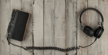 Ses kitabı konsepti. Kulaklıklar ve eski kitaplar ahşap masanın üzerinde. Metnin için en üstte boşluk var. Uzaktan eğitim kavramı.