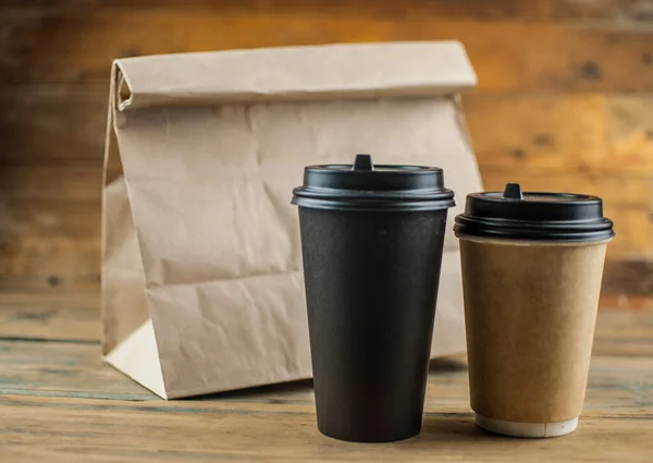 Take away paper coffee cup with lunch bag on wooden background