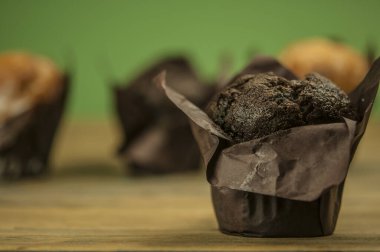 Ev yapımı çikolatalı ve vanilyalı kekler ahşap bir masada, üzerine pudra şekeri serpilmiş.