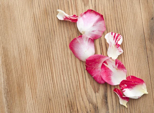 Rose petals lying down on a wooden table — Stock Photo, Image