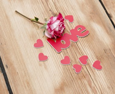 üzerinde kırmızı-beyaz gül ve dağınık çiçek yaprakları ve kelime aşk 