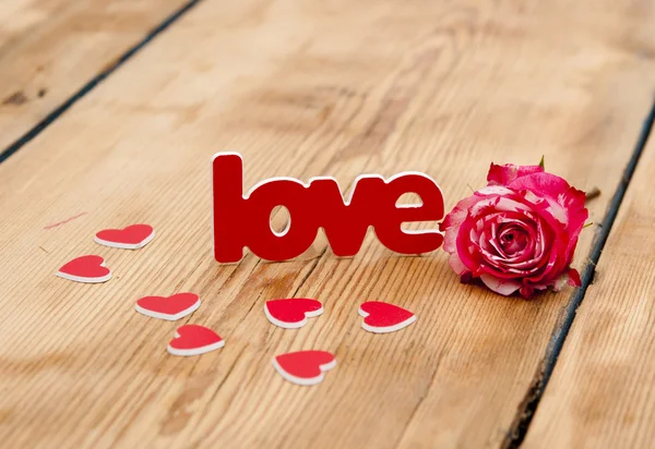 Red-white rose and scattered flower petals and the word love on — Stock Photo, Image