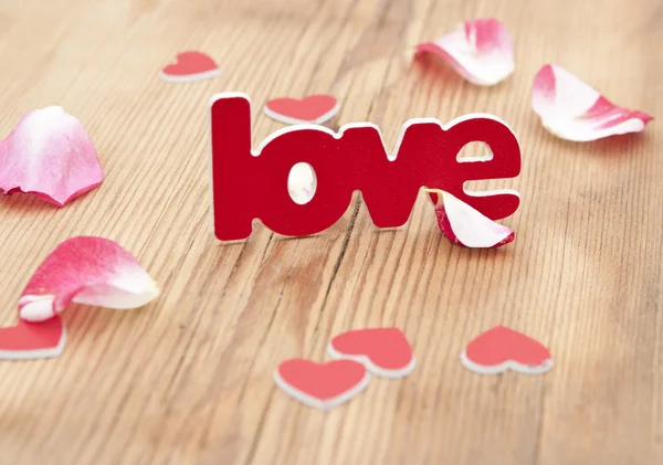 Love word and rose petal on a rustic background — Stock Photo, Image