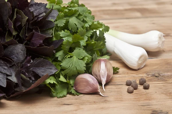 Fondo alimentare sul tavolo di legno: prezzemolo, basilico, aglio, pepe — Foto Stock