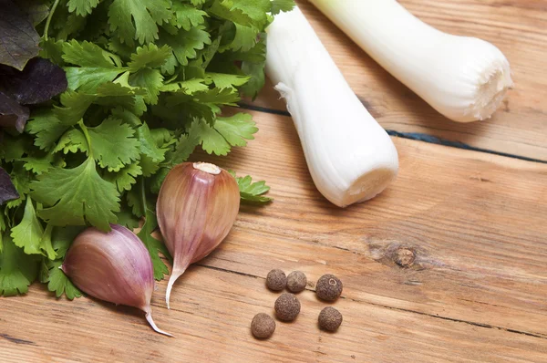 Fondo alimentare sul tavolo di legno: prezzemolo, basilico, aglio, pepe — Foto Stock