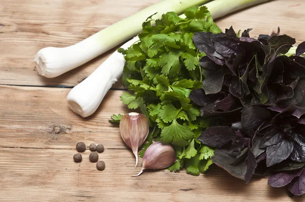 Fondo alimentare sul tavolo di legno: prezzemolo, basilico, aglio, pepe — Foto Stock