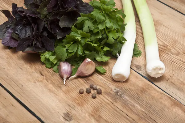 Fondo alimentare sul tavolo di legno: prezzemolo, basilico, aglio, pepe — Foto Stock