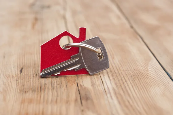 Symbool van het huis met zilveren sleutel op vintage houten achtergrond — Stockfoto