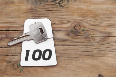 ahşap masa üzerindeki 100 Oda numarasıyla otel Süiti anahtarı 