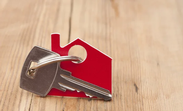 Símbolo de la casa con llave de plata sobre fondo de madera vintage —  Fotos de Stock