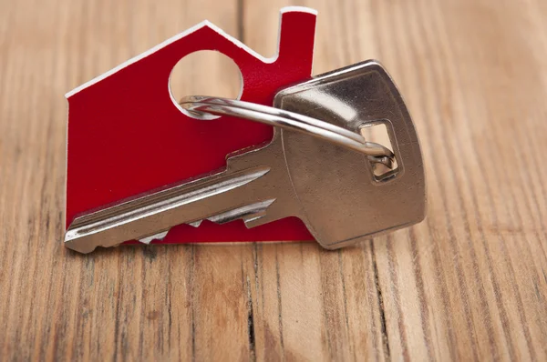 Símbolo de la casa con llave de plata sobre fondo de madera vintage — Foto de Stock