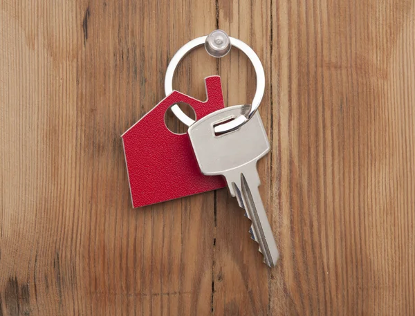 Symbol des Hauses mit silbernem Schlüssel auf Holzgrund — Stockfoto
