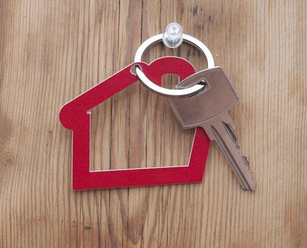 Símbolo de la casa con llave de plata sobre fondo de madera vintage — Foto de Stock