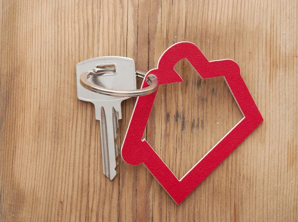 Símbolo da casa com chave de prata no fundo de madeira vintage — Fotografia de Stock